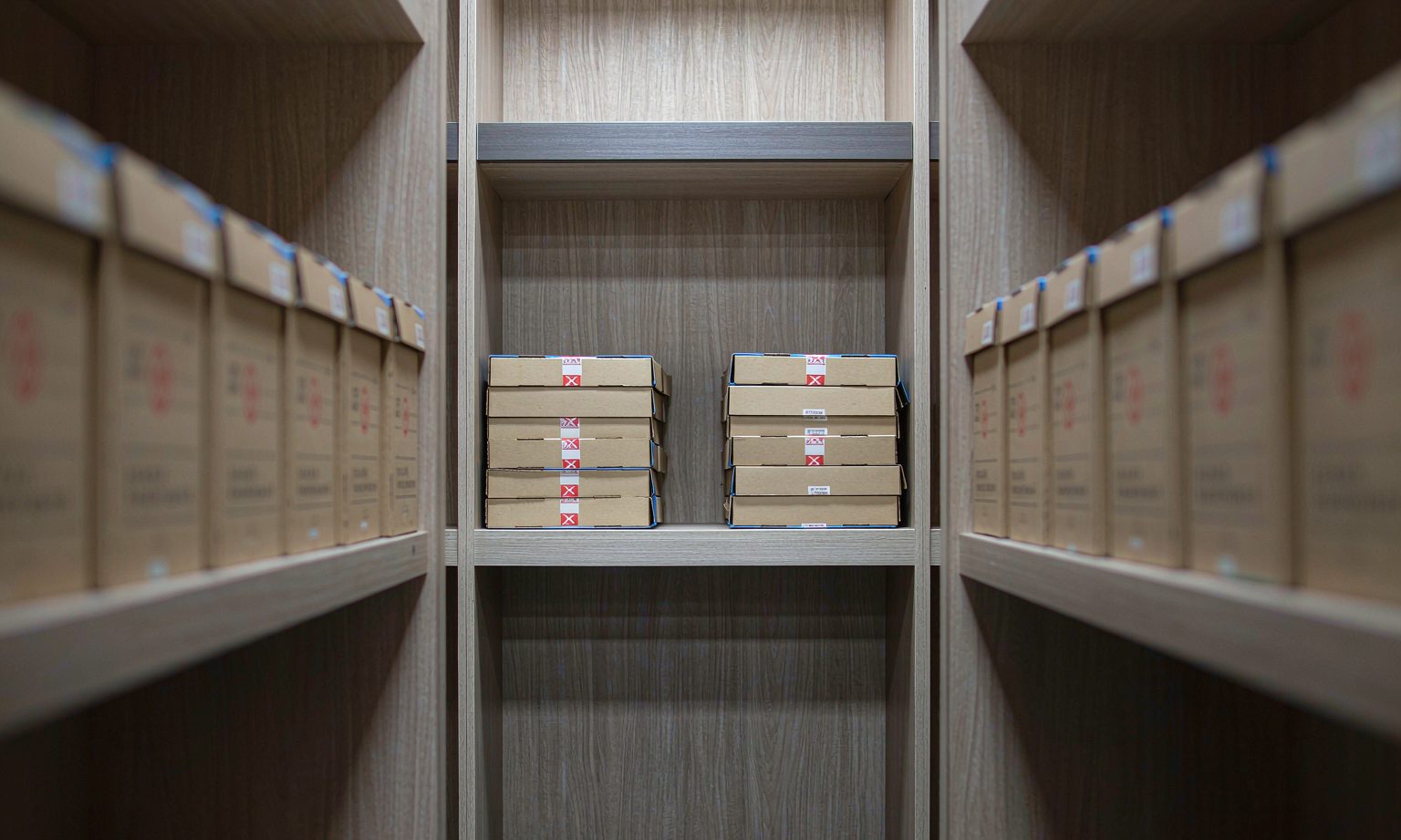 Sealed archive boxes stacked on a separated shelf bay in a records room