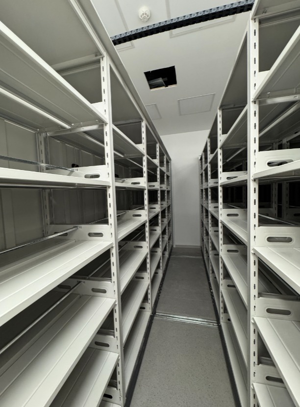 Bright open aisle between rows of mobile compact shelving in a library closed stack