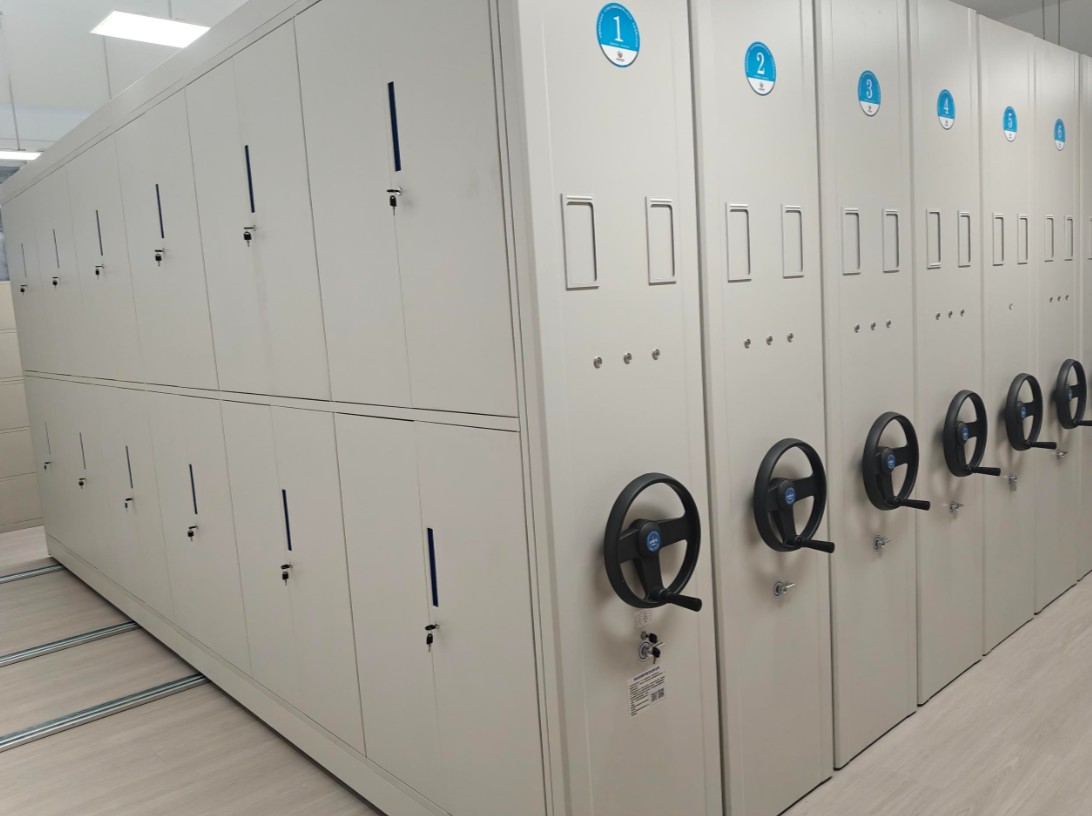 Closed mobile compact shelving run with hand-wheel cranks in a library stack