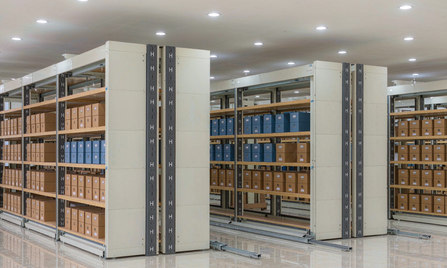 Open mobile compact shelving carriage with labelled archive boxes in a corporate records room