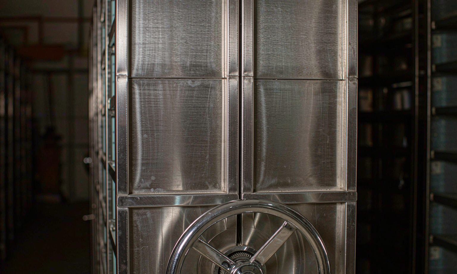 Steel vault-style compact shelving end panel with chrome hand wheel and lock